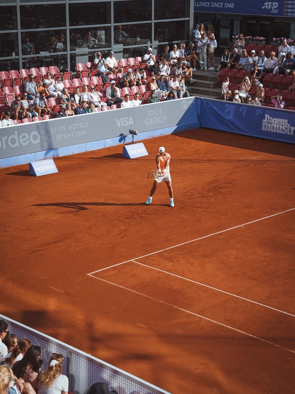Tennismatch på en grusbana inför fullsatt läktare